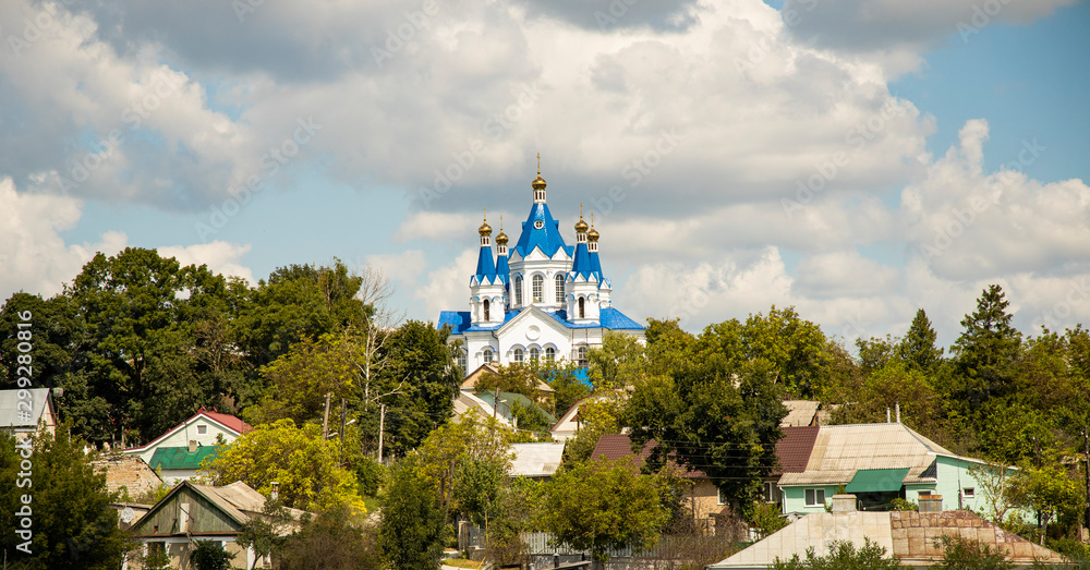 poor Russian village houses and beautiful white orthodox church with blue domes