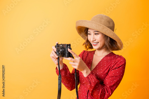 Portrait of fashionable young woman with vintage film camera for travelling concept. Isolated on orange background photo