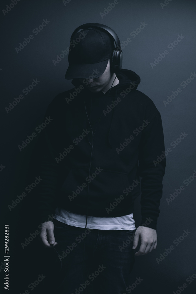 Junger Teenager mit Hoodie Pullover hört Musik mit Kopfhörer Junger Teenager mit Hoodie Pullover hört Musik mit Kopfhörer