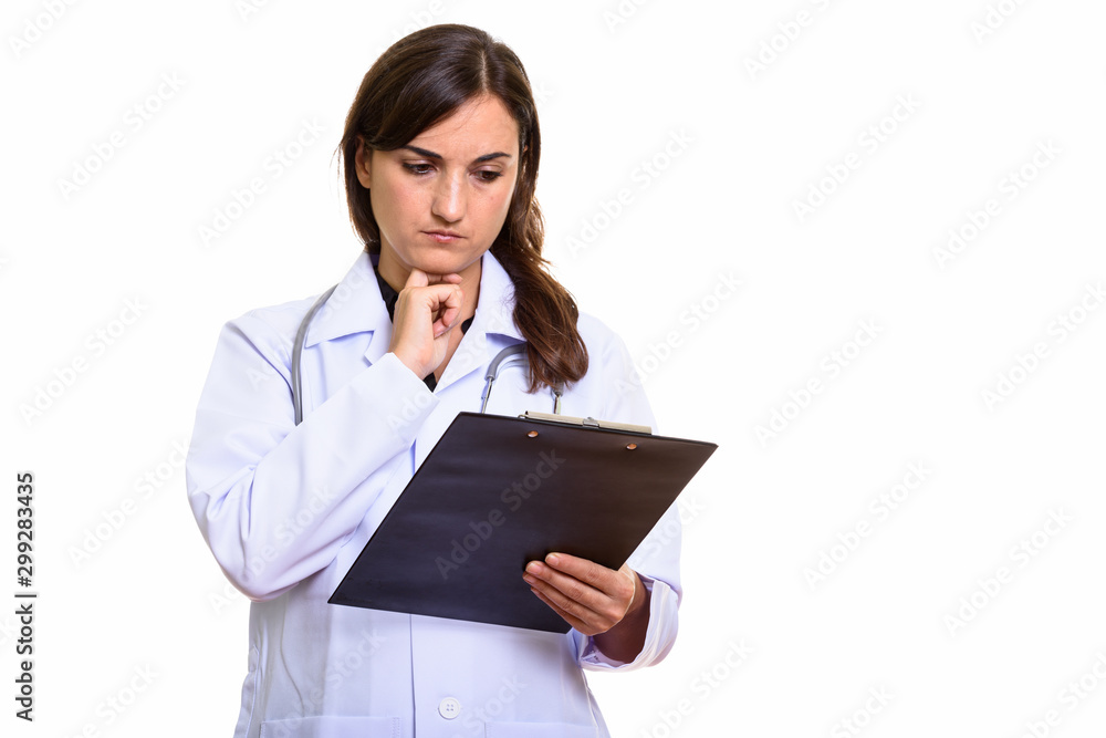Studio shot of beautiful woman doctor reading on clipboard while thinking Studio shot of beautiful woman doctor reading on clipboard while thinking