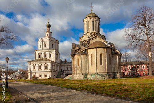 Two ancient Orthodox churches standing next to the monastery. In the foreground is a street lamp and a gravel path © igor_zubkov