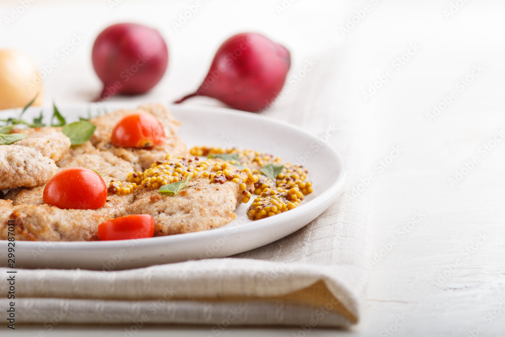 Fried pork chops with tomatoes and herbs on a white ceramic plate on a white wooden background. side view, close up. Fried pork chops with tomatoes and herbs on a white ceramic plate on a white wooden background. side view, close up.