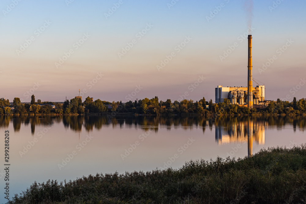 Old waste processing plant at the lake. Sunset