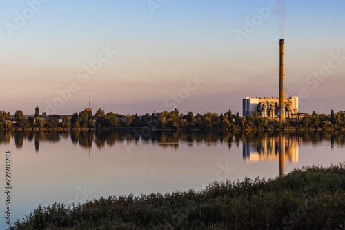 Old waste processing plant at the lake. Sunset