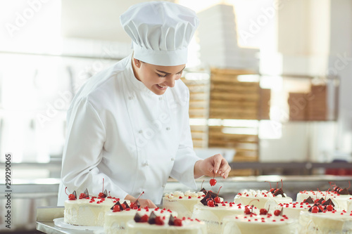 Obraz na płótnie Confectioner is holding a cake in her hand in the bakery.