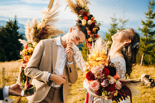 Newlyweds exchange rings during their beautiful wedding ceremony outdoors. .The groom kisses the hand of his wife