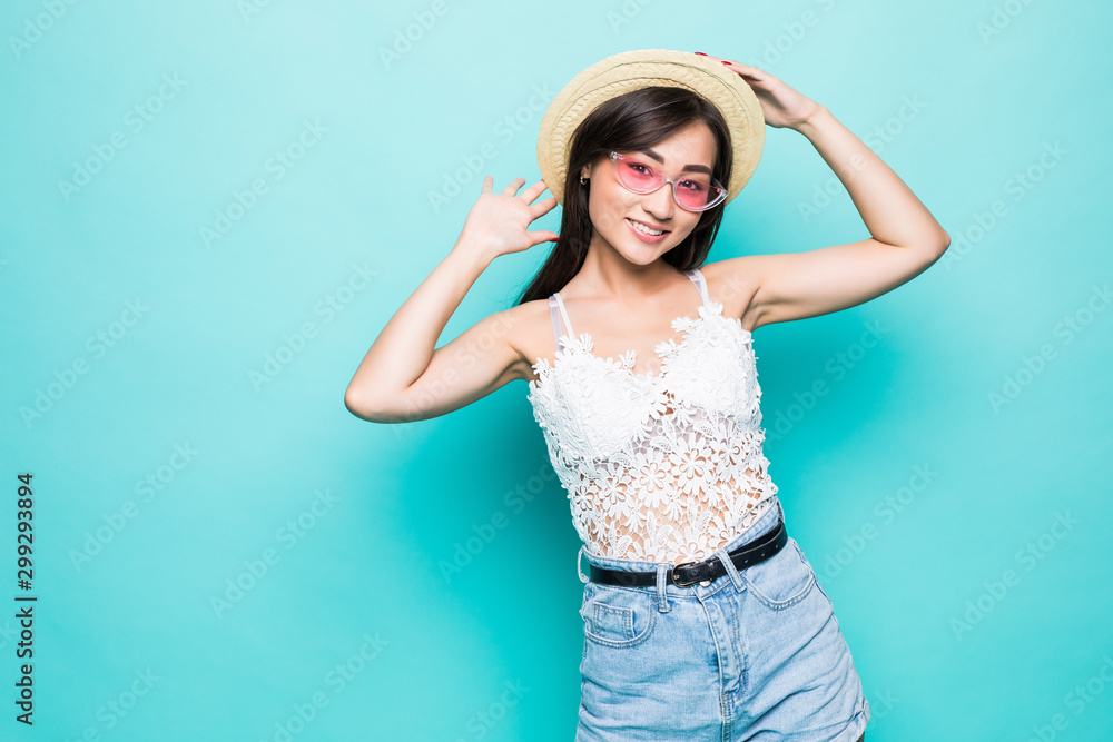 Young woman in sunglasses and straw hat against green background