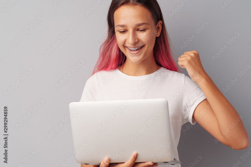 Happy young teen girl winner celebrating success over gray background