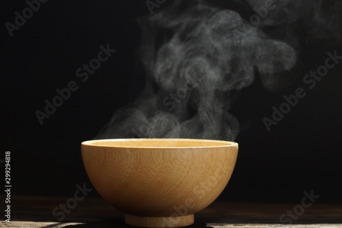 Hot soup in wooden bowl with steaming over it on white background