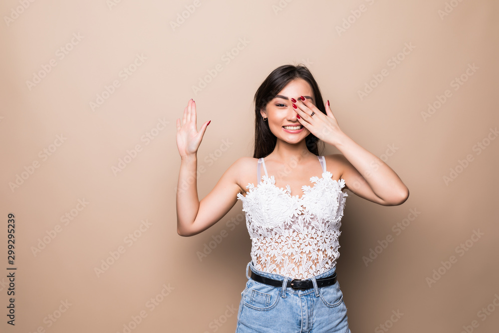 Happy surprised excited asian woman covering with hands her eye with blank copy space on beige background Happy surprised excited asian woman covering with hands her eye with blank copy space on beige background