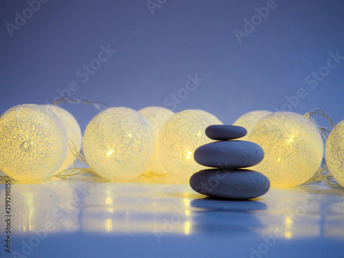 Stack of Zen stones on abstract dark background of Christmas garlands. Relax still Life with folded stones. Zen pebbles, stones, Spa-calm scenes to Christmas the soul of the imperturbable tranquility 