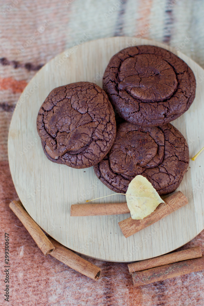 Fototapeta premium chocolate cookies on wooden plate, decorated with cinnamon and autumn leaf