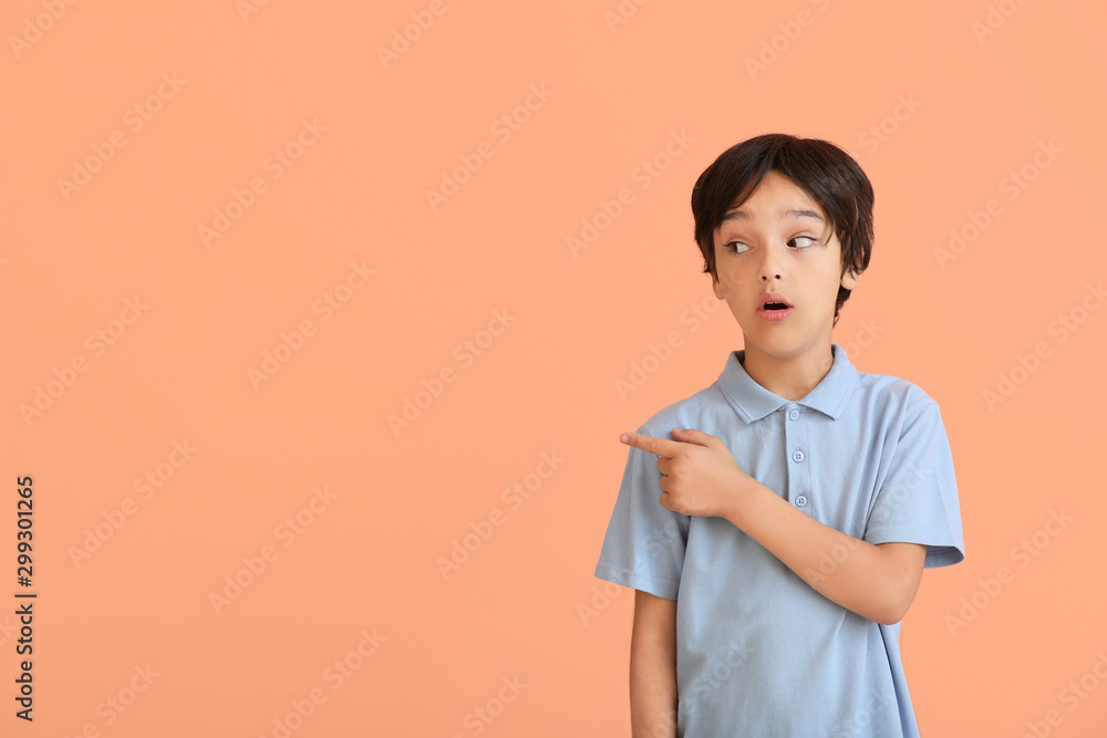 Surprised little boy pointing at something on color background Surprised little boy pointing at something on color background
