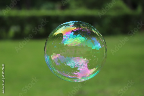 Close-up of big multicolored soap bubble flying with blurred background