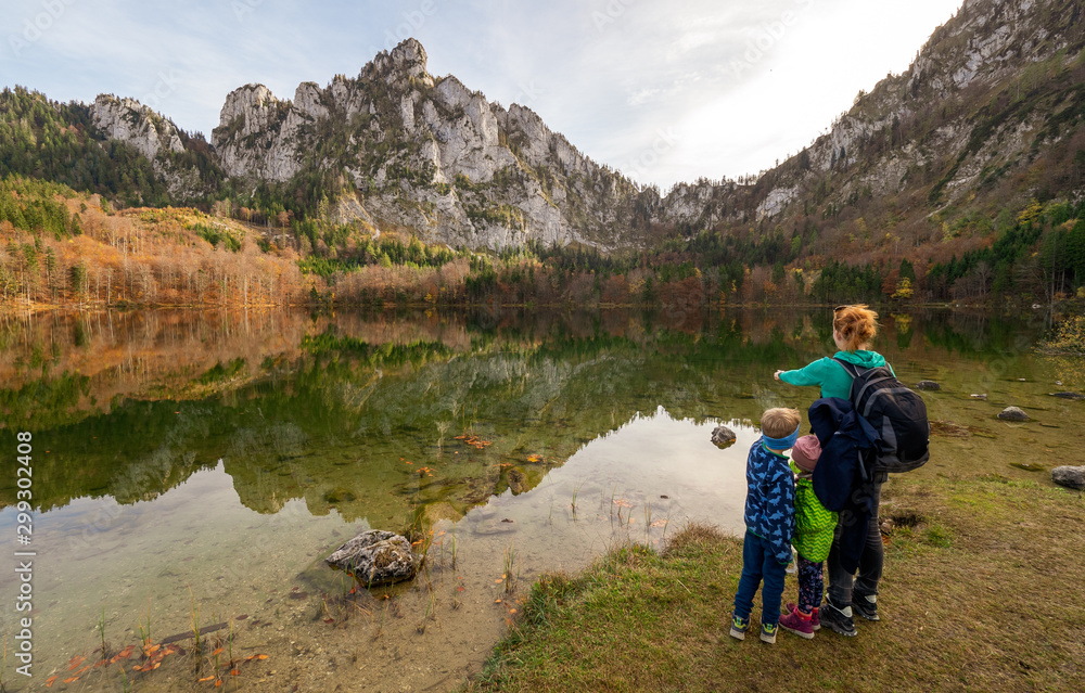 Mum and kids at the shore of the Laudachsee, Austria, with the stunning Katzenstein rising in the background and reflecting in the crystal clear water