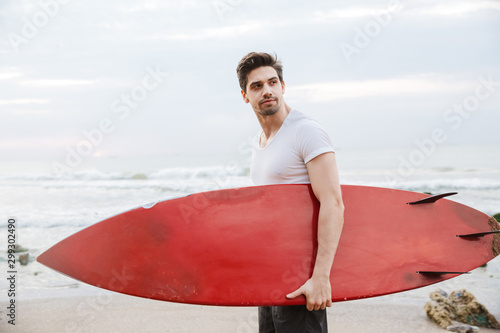 Man surfer with surfing on a beach outside.