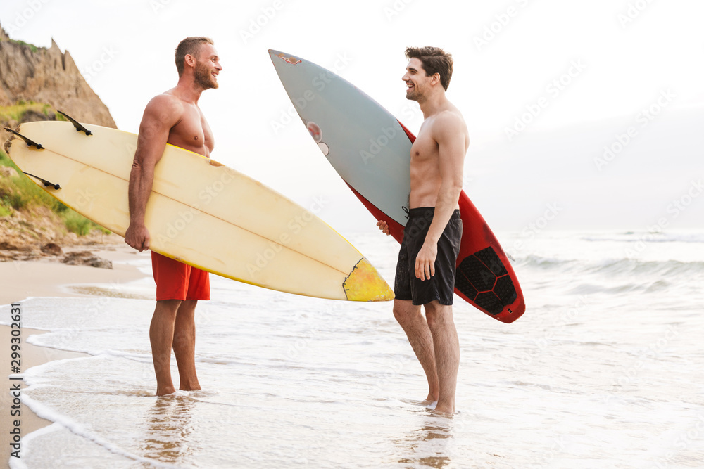 Positive two men surfers friends with surfings on a beach
