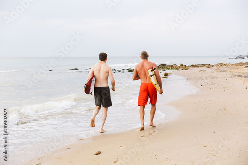 Two men surfers friends on a beach outside.