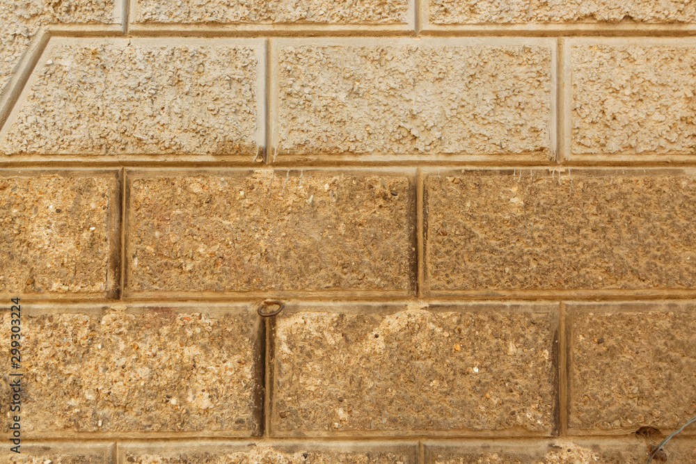 Stone brick wall made by non uniform textured concrete blocks with flat cuts.