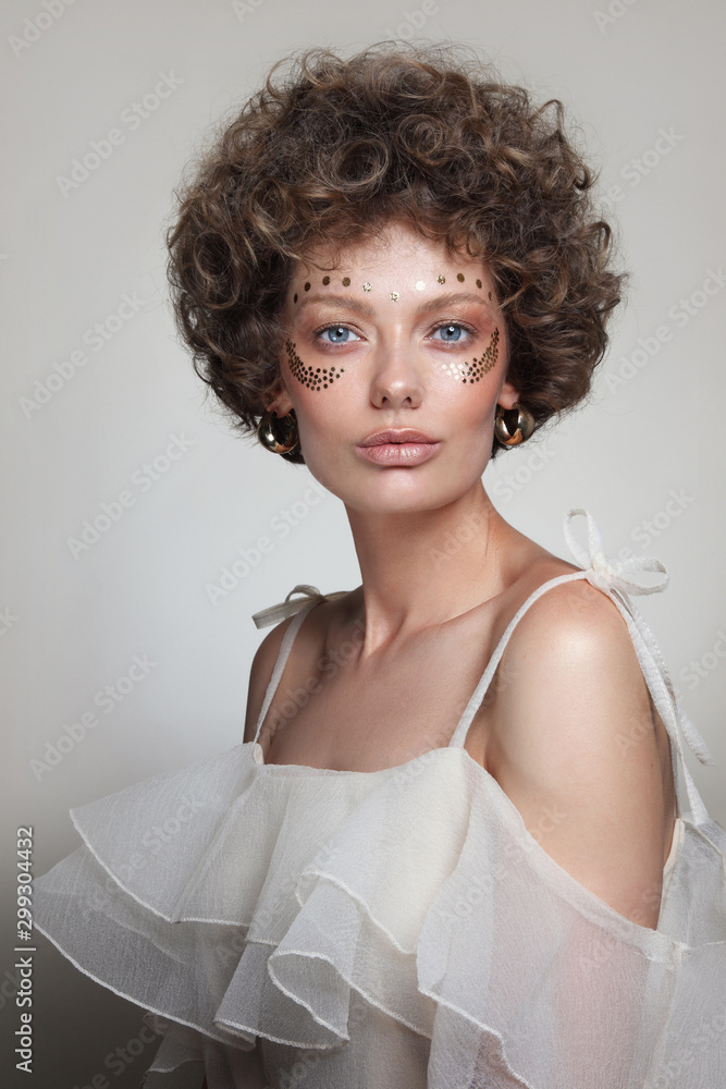 Vintage style portrait of young beautiful woman with curly hair and fancy  makeup Stock Photo