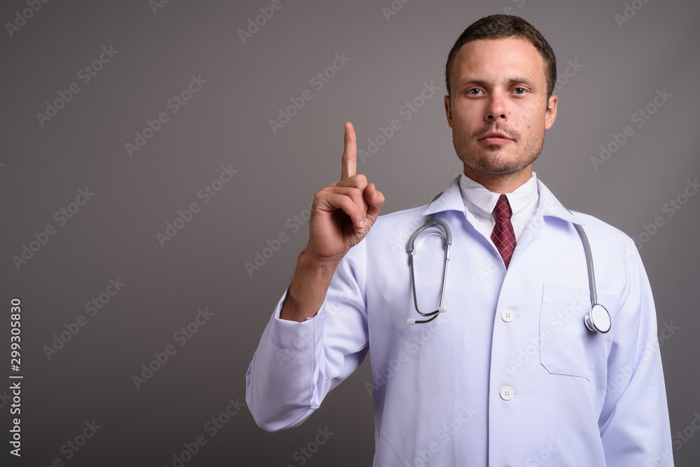 Portrait of handsome man doctor against gray background Portrait of handsome man doctor against gray background