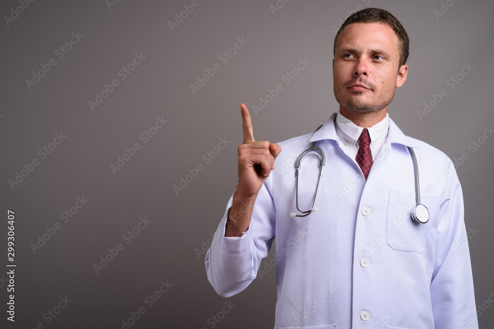 Portrait of handsome man doctor against gray background Portrait of handsome man doctor against gray background
