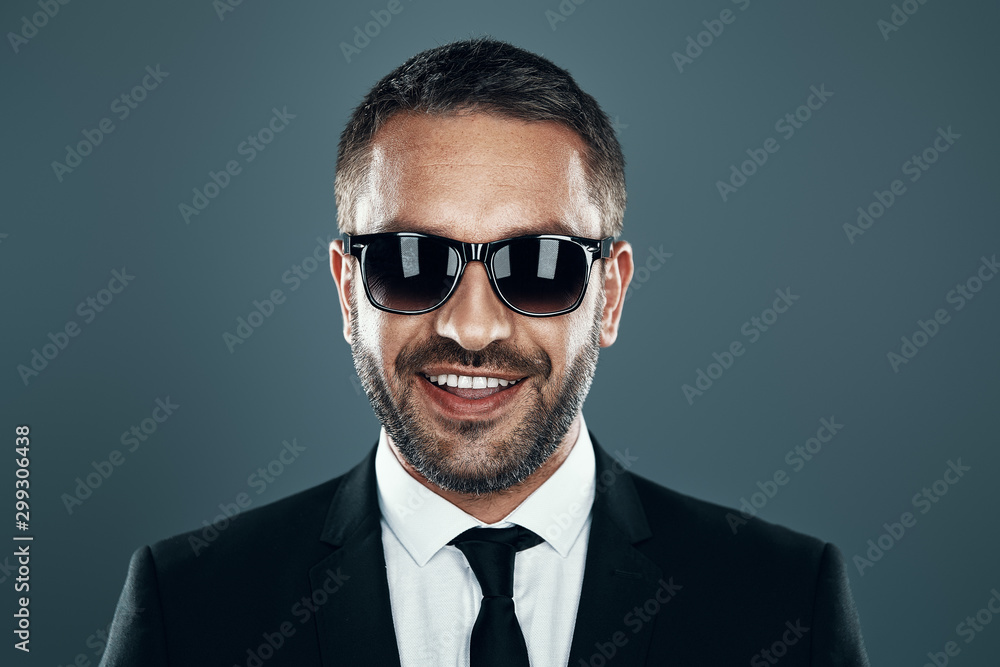 Charming young man in formalwear smiling while standing against grey background Charming young man in formalwear smiling while standing against grey background