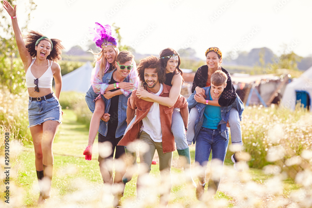 Group Of Friends Walking Back To Tent After Outdoor Music Festival With Men Giving Women Piggybacks Group Of Friends Walking Back To Tent After Outdoor Music Festival With Men Giving Women Piggybacks