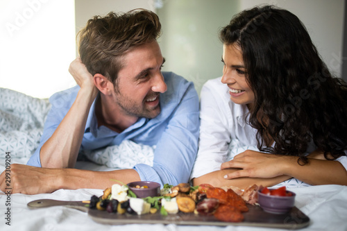 Happy young couple eat breakfast in bed in morning