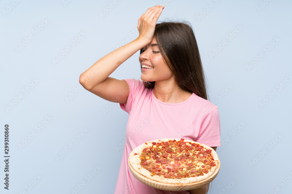 Pretty young girl holding a pizza over isolated blue wall has realized something and intending the solution