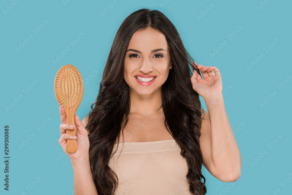 happy girl holding hair brush and touching shiny hair isolated on blue happy girl holding hair brush and touching shiny hair isolated on blue