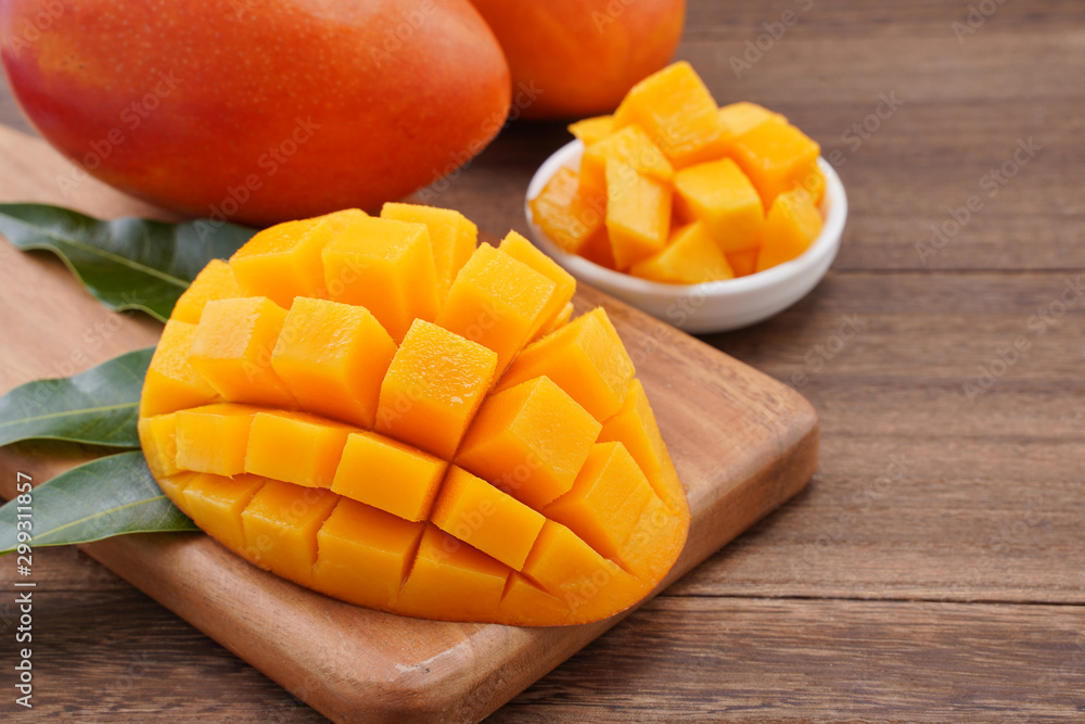 Fresh mango,beautiful chopped fruit with green leaves on dark wooden table background. Tropical fruit design concept. Flat lay. Top view. Copy space Fresh mango,beautiful chopped fruit with green leaves on dark wooden table background. Tropical fruit design concept. Flat lay. Top view. Copy space