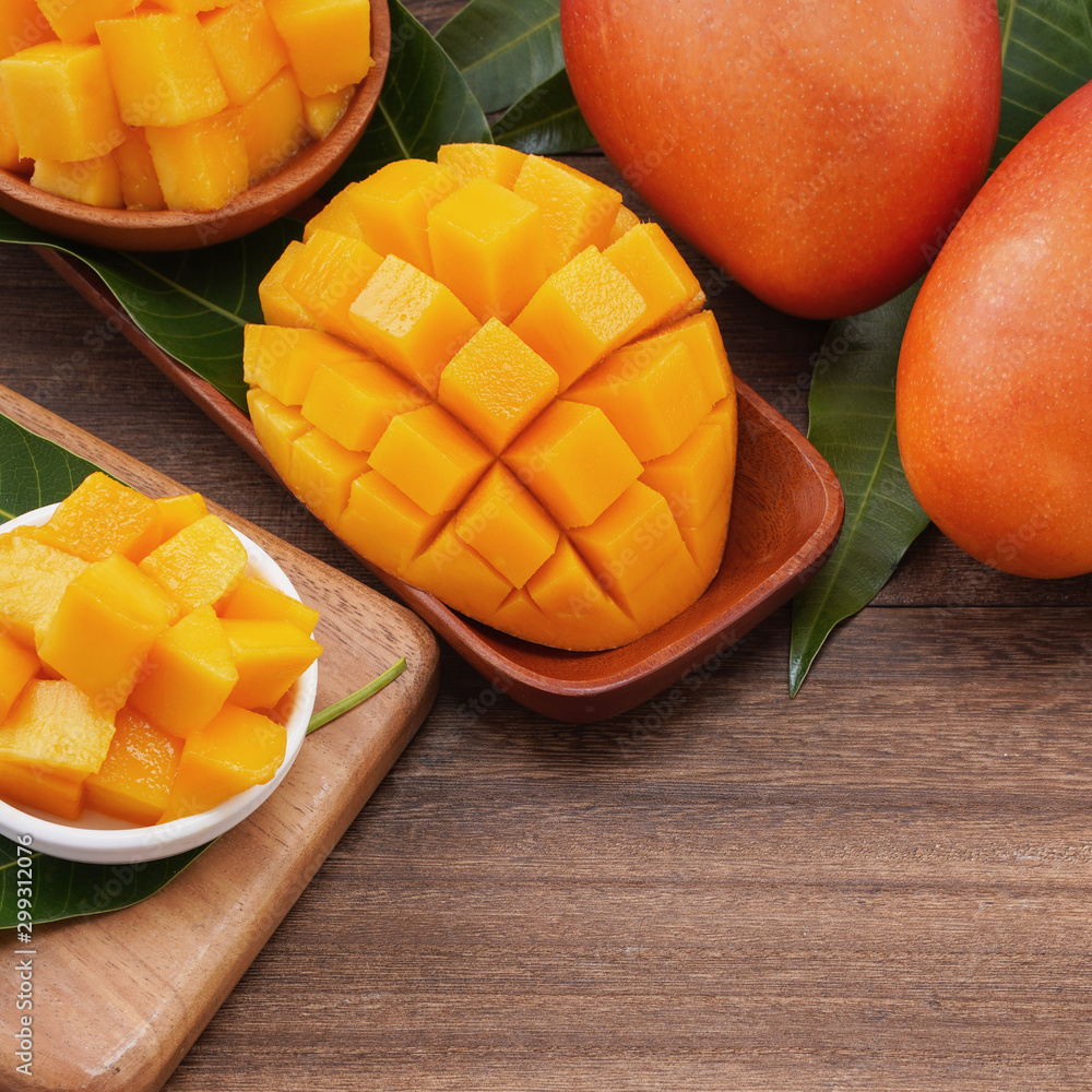 Fresh mango,beautiful chopped fruit with green leaves on dark wooden table background. Tropical fruit design concept. Flat lay. Top view. Copy space Fresh mango,beautiful chopped fruit with green leaves on dark wooden table background. Tropical fruit design concept. Flat lay. Top view. Copy space