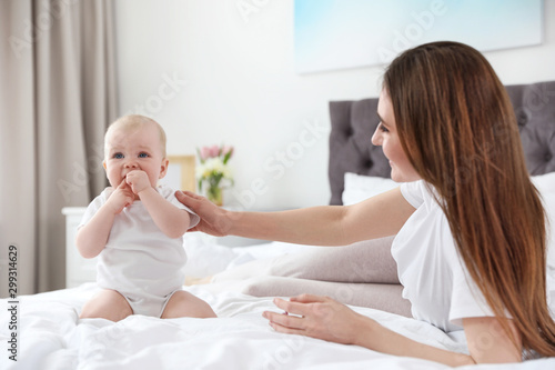 Happy mother with little baby on bed at home