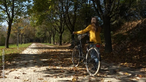 SLOW MOTION Young active woman riding a black city bicycle on a sunny autumn day in a park