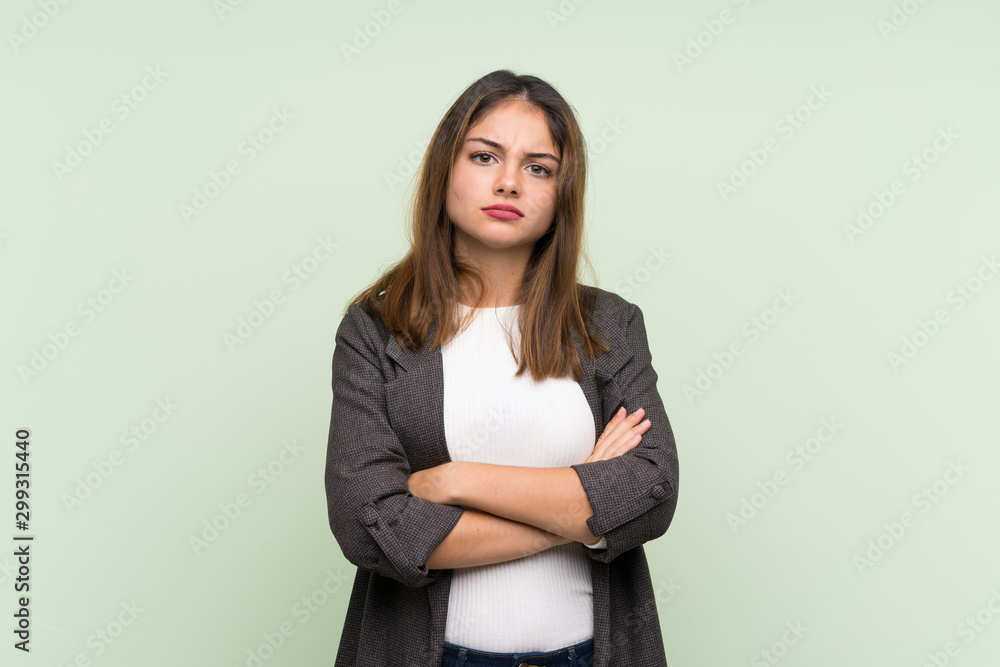 Young brunette girl with blazer over isolated green background feeling upset Young brunette girl with blazer over isolated green background feeling upset
