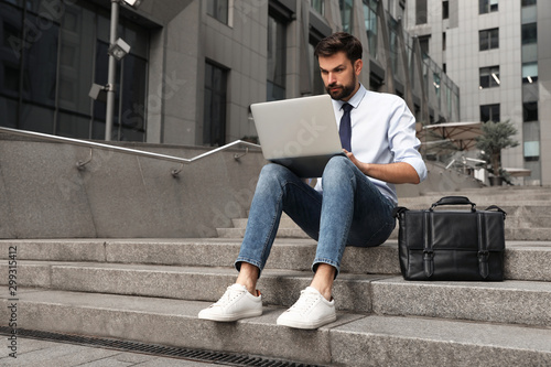 Handsome man working with laptop on city street photo