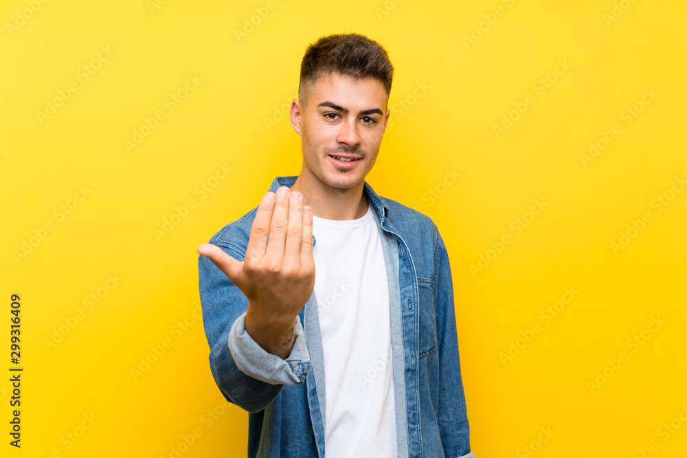 Young handsome man over isolated yellow background inviting to come Young handsome man over isolated yellow background inviting to come