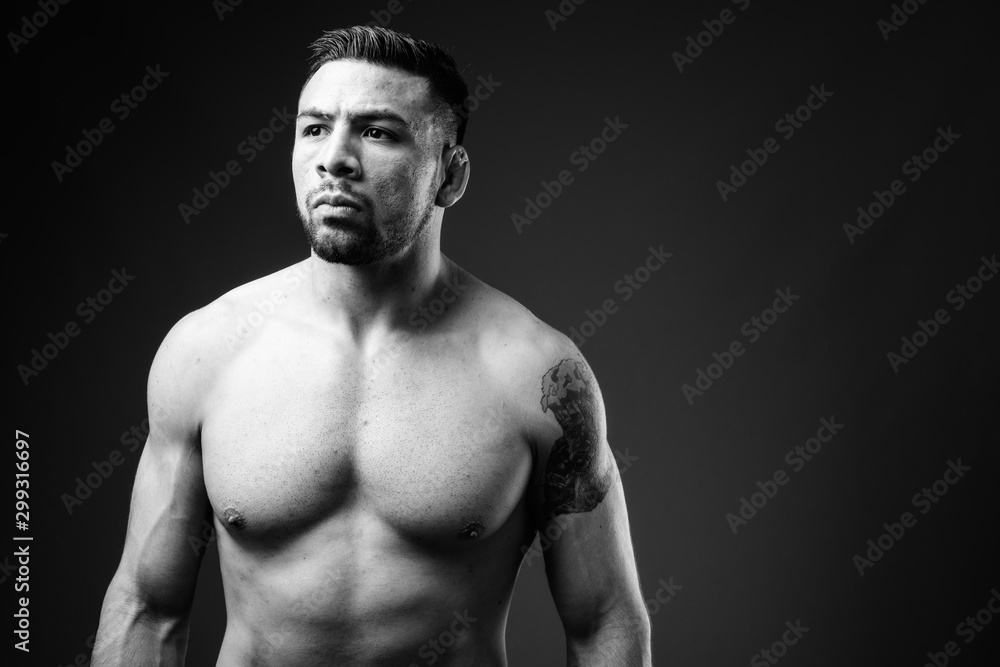 Young muscular Hispanic man shirtless against black background Young muscular Hispanic man shirtless against black background