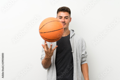 Sport man over isolated white wall with ball of basketball © luismolinero