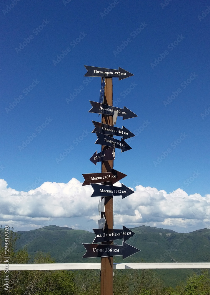 Obraz premium tourist signpost in the mountains. arrows and city names against a blue sky