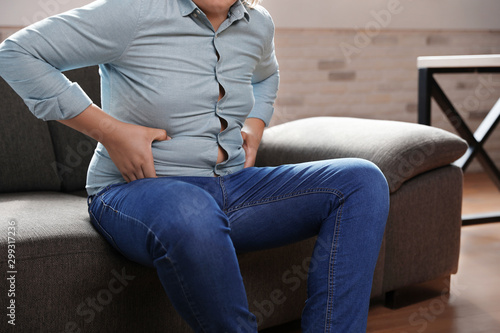 Overweight boy sitting on sofa at home  closeup view