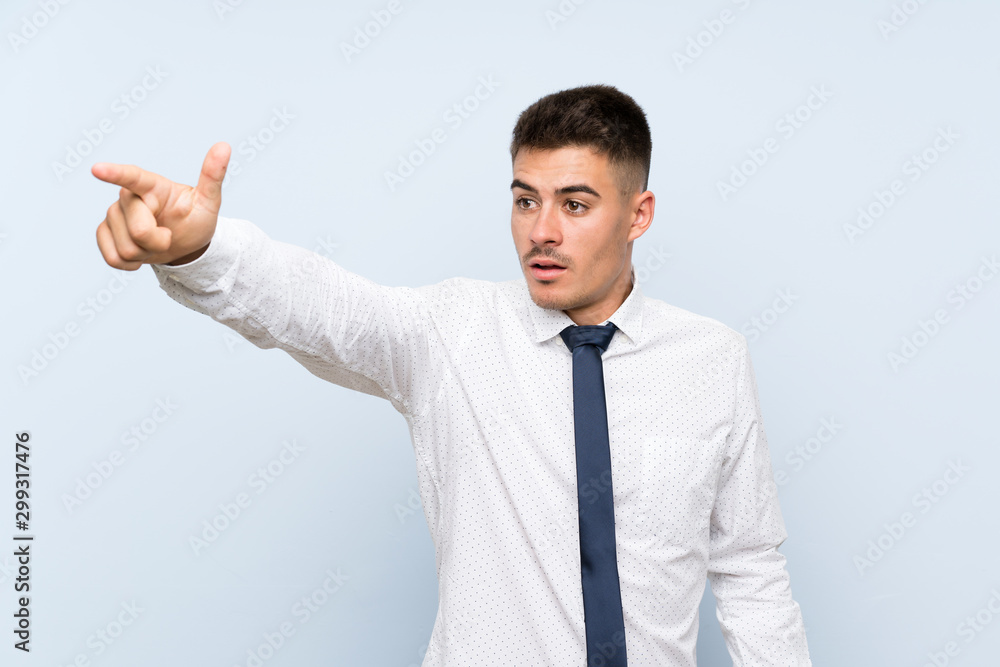 Handsome businessman over isolated blue background pointing away Handsome businessman over isolated blue background pointing away