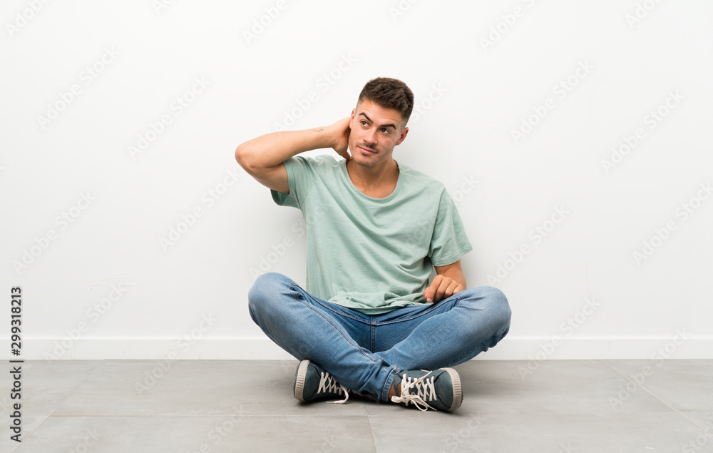 Young handsome man sitting on the floor laughing Young handsome man sitting on the floor laughing