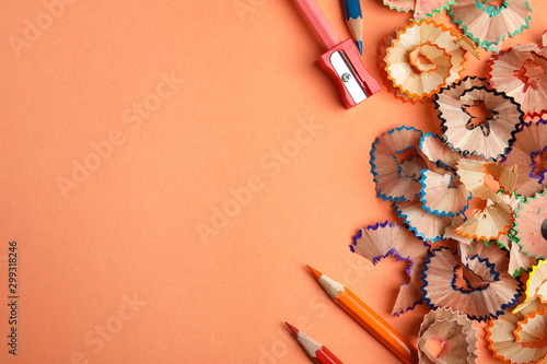 Fotografía Color pencils, sharpener and shavings on orange background, flat lay