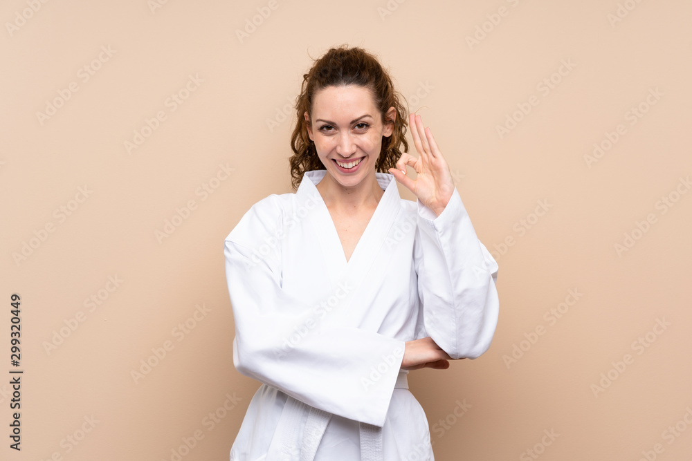 Young woman doing karate showing ok sign with fingers Young woman doing karate showing ok sign with fingers