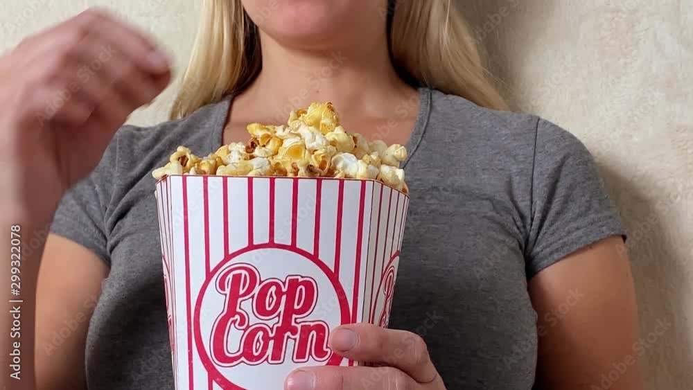 Girl watching tv and eating popcorn seated on sofa at home Girl watching tv and eating popcorn seated on sofa at home