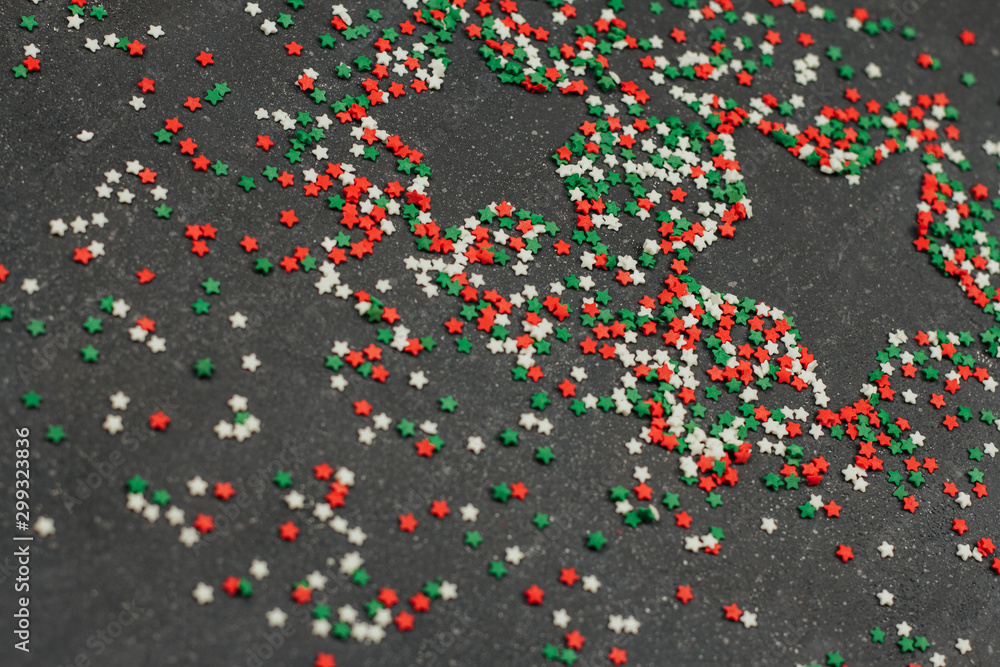 tricolor confectionery confetti in the shape of stars on a dark gray background. decor for Christmas baking.	