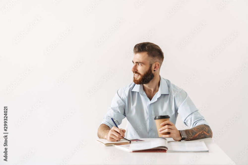 Image of brunette man sitting at table and studying with exercise books Image of brunette man sitting at table and studying with exercise books