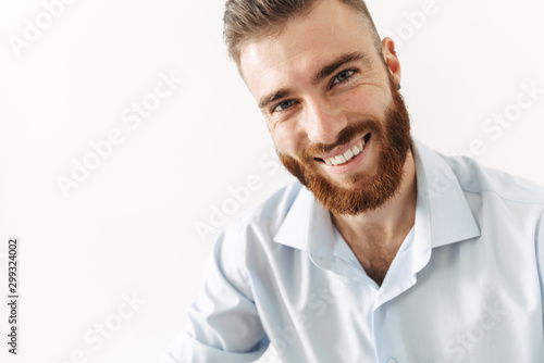 Image of young handsome bearded man in shirt smiling at camera